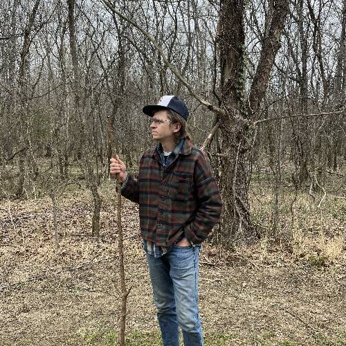 Sam Steffen holding walking stick in the woods